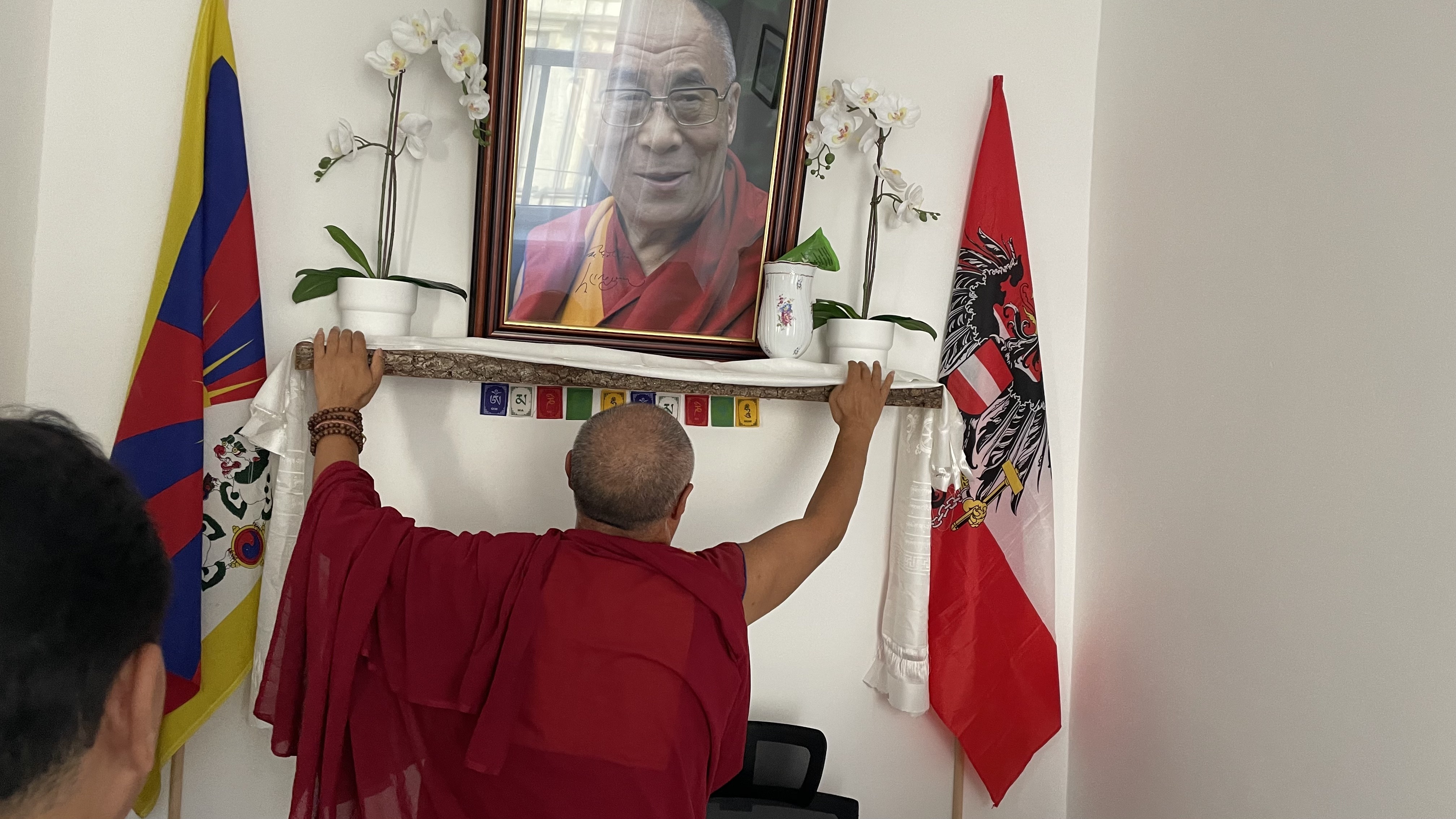 Geshe Lobsang Soepa hängt einen tibetischen Schal vor das Bild Seiner Heiligkeit dem 14. Dalai Lama von Tibet